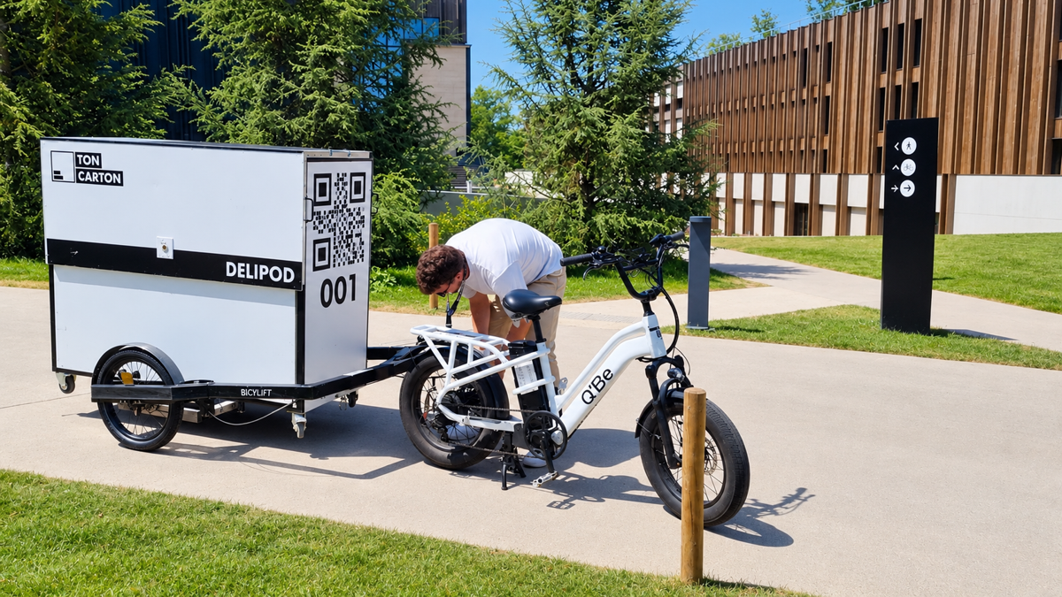 Un Delipod posé sur une remorque Bicylift, à côté d'un vélo à assistance électrique